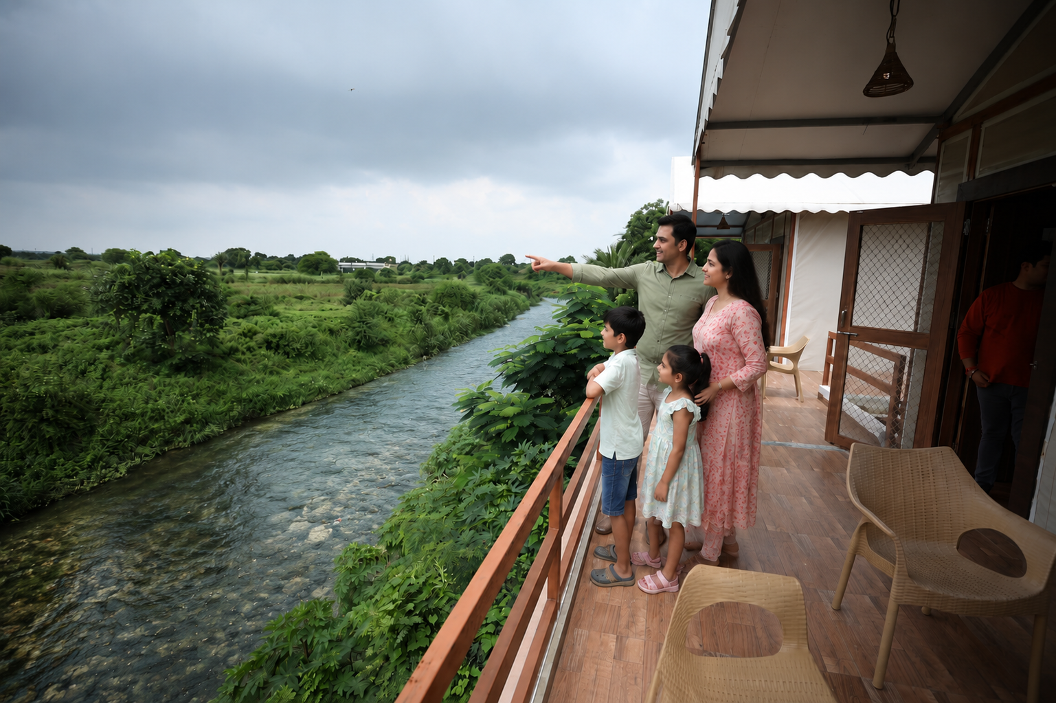 Family on a riverside balcony pointing across the water